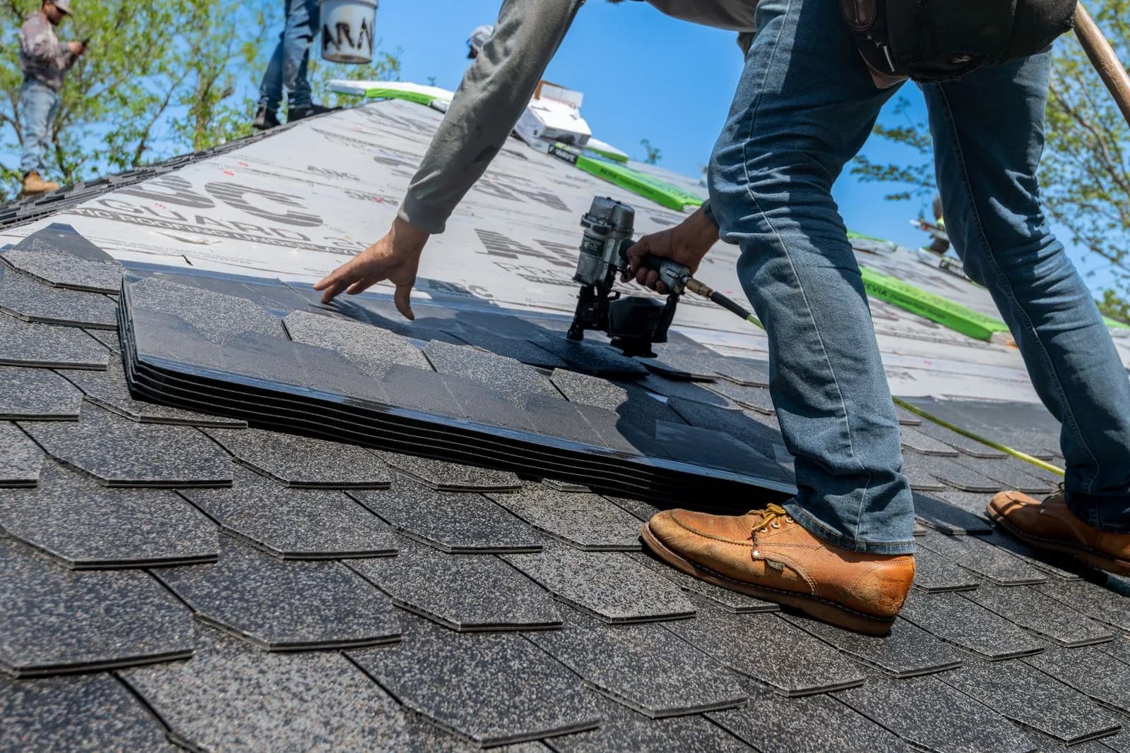 Roofing crew installing shingles on a New England home